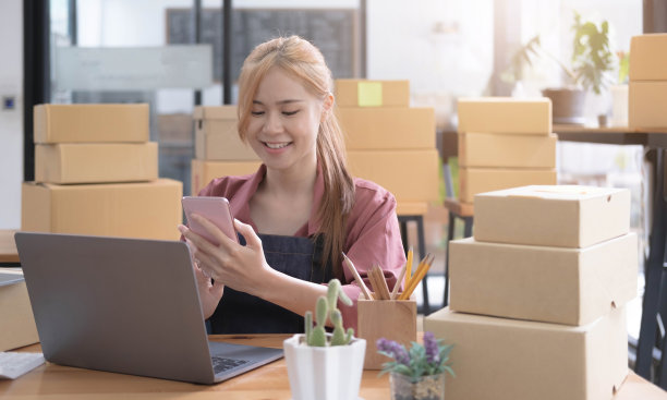 女小企业主用手机记录顾客的订单。中小企业企业家或自由职业者的生活方式的概念。图片下载