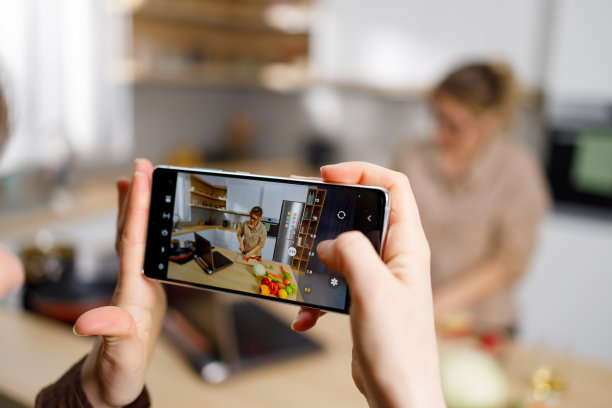 女孩用智能手机录下妈妈做饭的视频图片下载