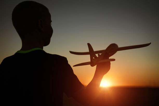 男孩在夏日黄昏玩玩具飞机图片下载