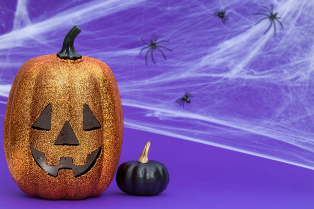 万圣节派对的现代明信片。南瓜杰克，黑色南瓜，蜘蛛网，蜘蛛，时髦的紫色背景。带有文本复制空间的横幅。图片下载