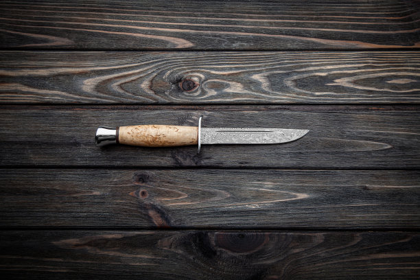 木柄猎刀：大马士革钢刀片，复古木板背景图片下载