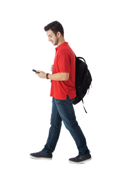 拉丁男学生边走边低头看手机图片下载