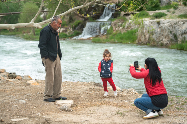 中年妇女在户外为女孩和老年祖父拍照图片下载