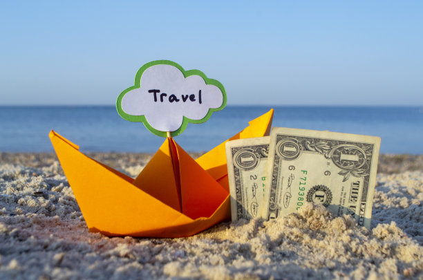 两张一美元的纸币半埋在沙子里，橙色的纸船图片下载