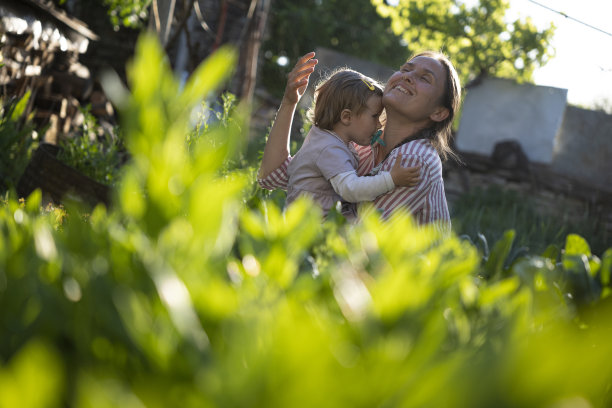 母亲和婴儿一起在夕阳下园艺。图片下载