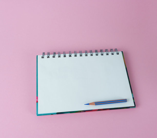 打开的笔记本，粉色背景上有一支蓝色铅笔。概念-计划，日常事务。图片下载