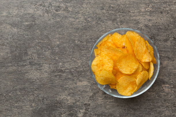 土豆片在碗上隔离的彩色背景。碗里的美味脆薯片。空间的文本。俯视图图片下载