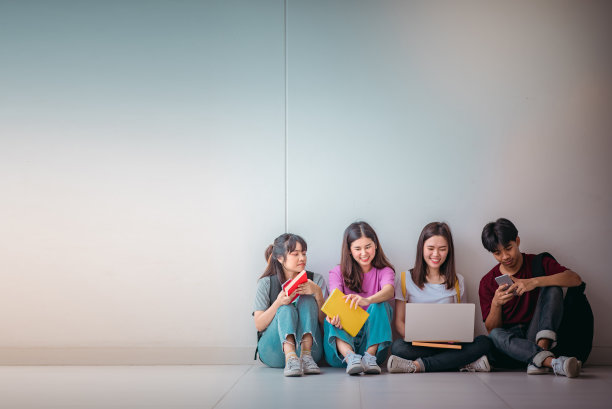 亚洲学生群体使用笔记本电脑、数码平板电脑以及墙上的拷贝空间。生活方式与信息技术小工具教育或社交网络的概念。图片下载