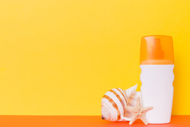 海滩配件。保湿防晒乳液瓶的UVB皮肤保护在夏天与彩色背景的贝壳。用拷贝空间模拟图片下载