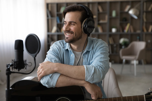 快乐的年轻人在专业耳机抱吉他看一边图片下载