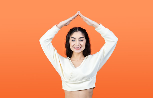 美丽的亚裔印度裔妇女显示了她头上的房子的姿态。梦想自己的房子的概念。图片下载