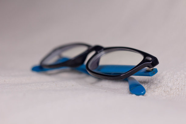 黑色镜框和蓝色太阳穴的眼镜在明亮的背景上特写。图片下载