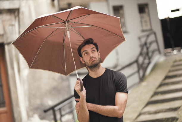 拿着雨伞，抬头看天气的年轻男人图片下载