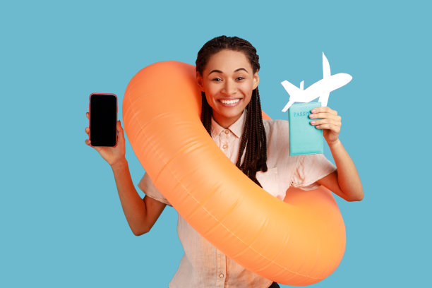 女人拿着橙色的橡胶戒指，纸飞机和手机，计划出国度假。图片下载