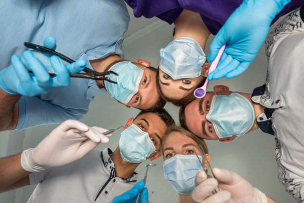 一群兴高采烈的牙医和他们的助手站在牙科诊所里，开心地笑着。图片下载