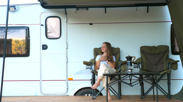 女游客坐在拖车附近，享受自由。旅游人群的概念图片下载