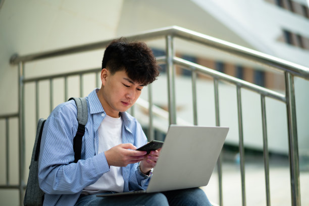 亚洲年轻帅哥在地铁站使用笔记本电脑图片下载
