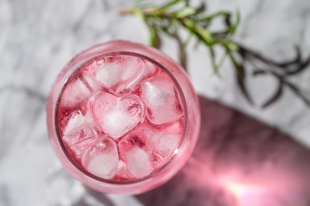 一杯有冰块和迷迭香背景的粉红色饮料图片下载