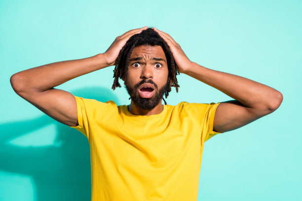 惊慌失措的黑色皮肤男子的照片肖像手持头部与两只手孤立在生动的青色背景图片下载