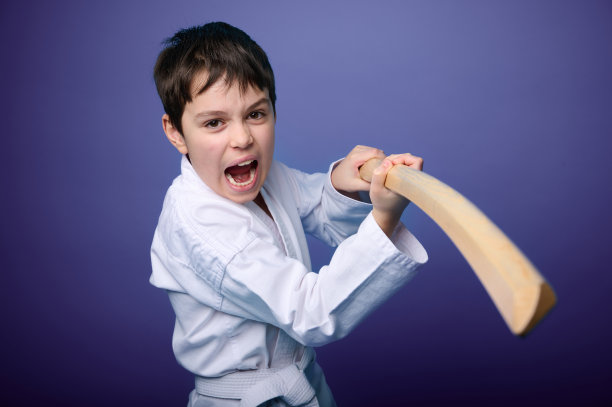 身穿白色和服的白人少年手持木制武士刀，摆出战斗姿势。合气道战士。东方武术概念图片下载