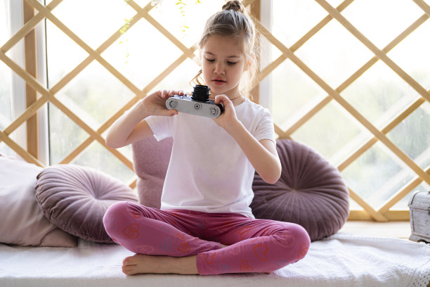 小女孩在家里玩古董相机图片下载