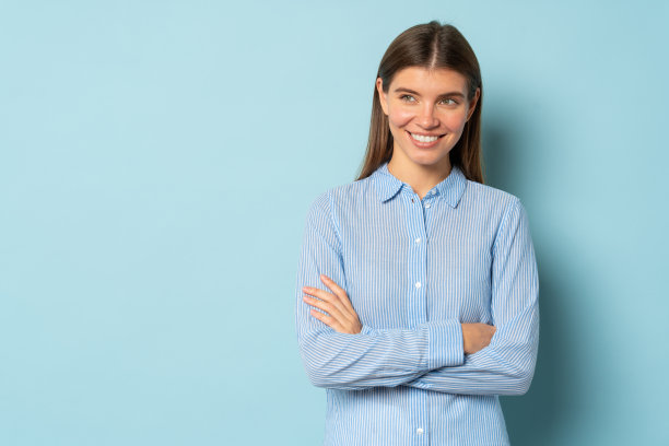 相当沉思、聪明、自信的女孩站着，双臂交叉在蓝色的背景上，有拷贝空间图片下载