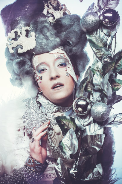 一个美丽的女人穿着圣诞嘉年华的服装，在圣诞装饰和银色树叶的框架中摆姿势。图片下载