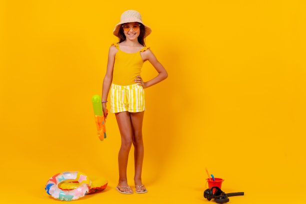 小女孩在黄色背景下玩夏天的玩具图片下载