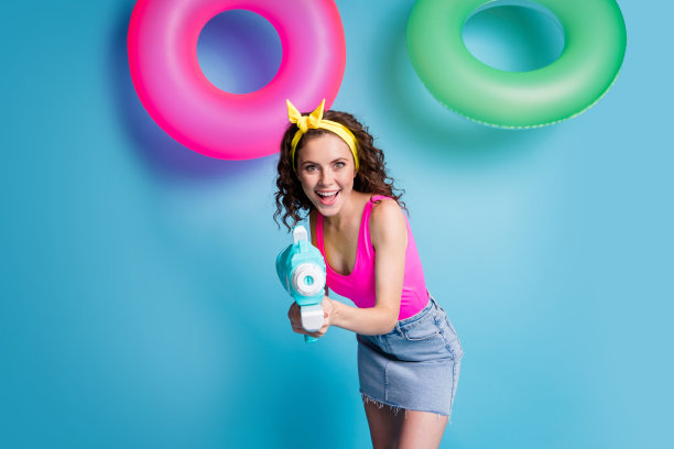 年轻兴奋的女孩的照片快乐积极的微笑玩游戏射击水枪孤立在蓝色的背景图片下载