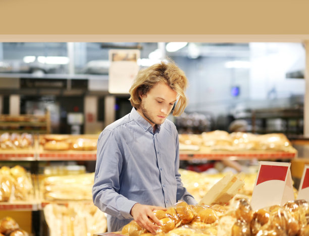 一个男人在超市里挑选面包图片下载