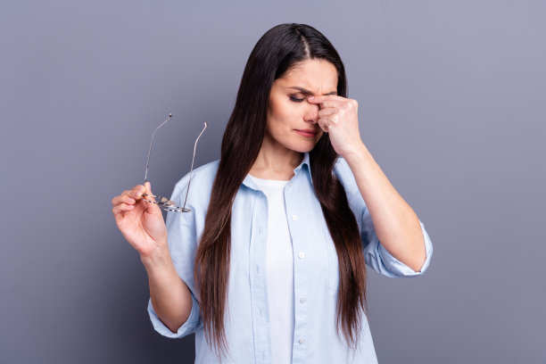照片心烦累年轻女士穿着蓝色衬衫手臂眼镜鼻子孤立灰色背景图片下载