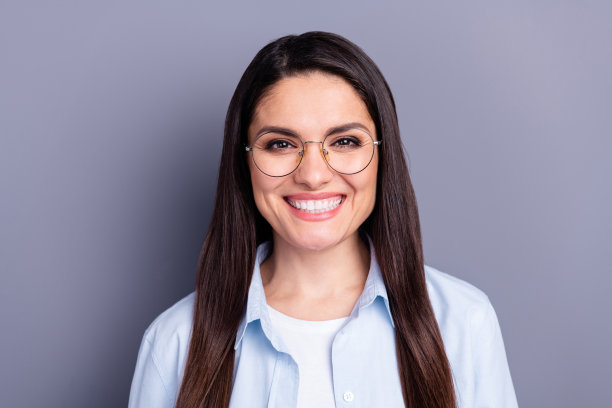 照片可爱甜美的年轻女士穿着蓝色衬衫眼镜微笑孤立的灰色背景图片下载