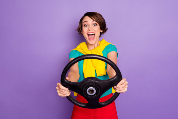 疯狂兴奋的女士张口抱方向盘的照片穿系套头衫t恤孤立的紫罗兰色背景图片下载