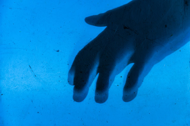 蓝色墙上的黑色剪影。粗糙的染色墙壁上一只珍爱的手的轮廓。具有多种设计挑战的创造性多任务处理背景。有选择性的重点。副本的空间。图片下载
