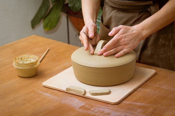 陶艺课上，女陶艺家在锅上安装把手。陶艺工作室的陶工车间图片下载