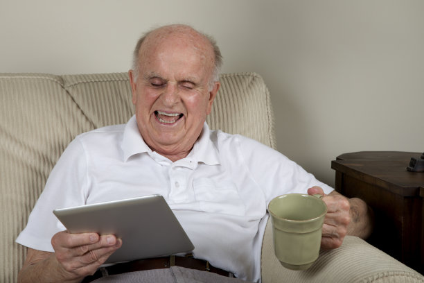 老人在家笑着看电子平板电脑图片下载