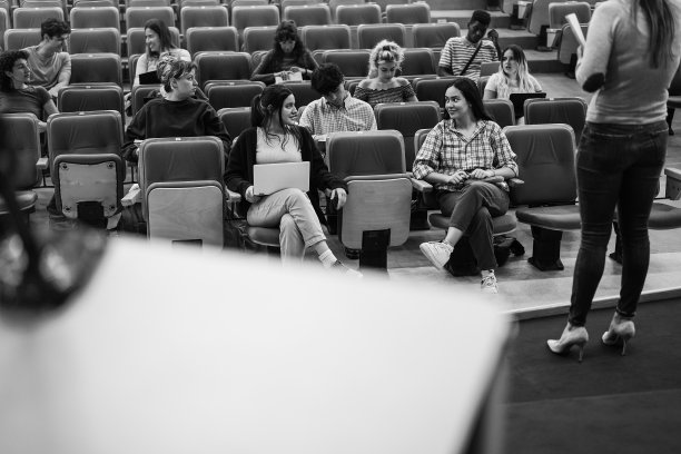 年轻的学生在礼堂大学听会议研讨会-关注前面的女孩的脸-黑白编辑图片下载