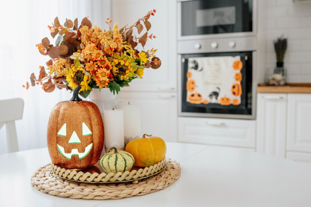 一个花瓶，一个南瓜，托盘上放着蜡烛。背景是斯堪的纳维亚风格的白色厨房内部。家和舒适的概念。万圣节的秋季装饰。图片下载