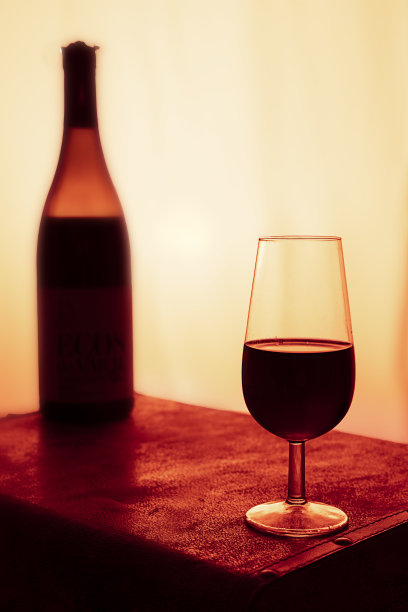 一瓶和一杯红酒与温暖的夕阳背景和红玫瑰装饰图片下载