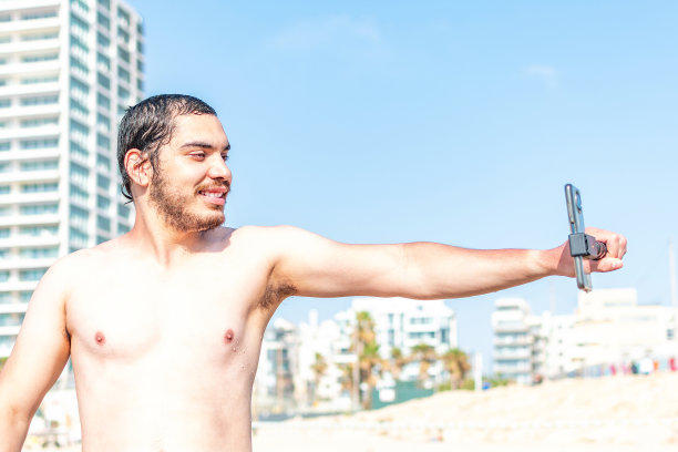 在海滩上快乐的男人用智能手机自拍图片下载