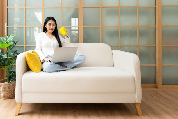 快乐的年轻女性在家在线工作和开会。生活方式自由，在客厅喝咖啡放松和冷静，自然花园背景。生活方式的概念图片下载