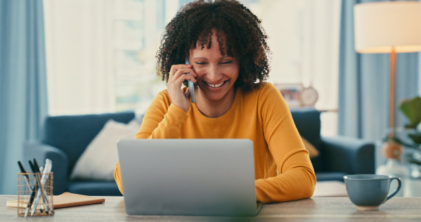 一名年轻女子在家工作时使用笔记本电脑和智能手机图片下载