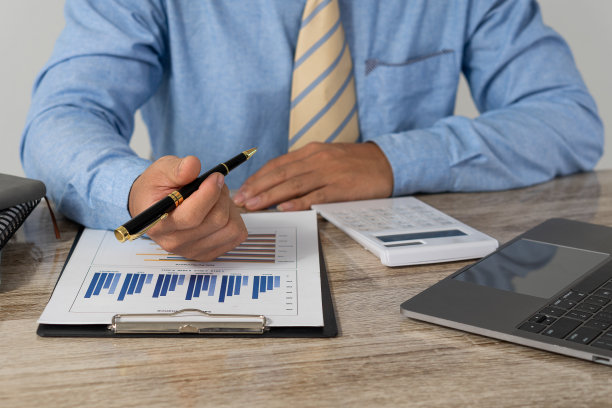 特写照片。商人拿着笔，用财务营销网络图指着财务文档，在笔记本电脑上工作。网络会计的概念图片下载