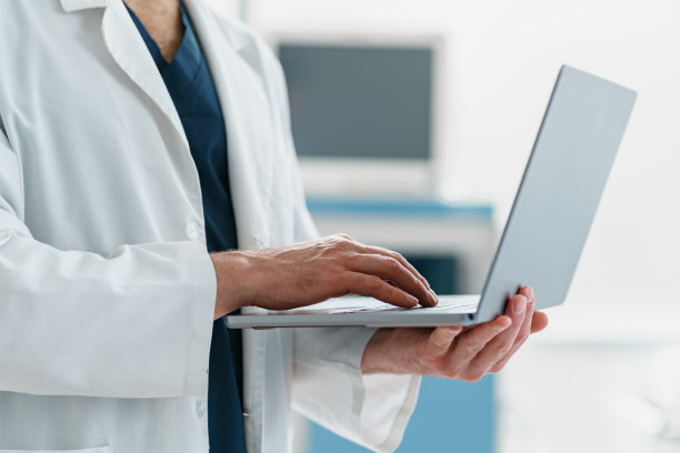 现代诊所手术室中医生用手提电脑的手特写图片下载