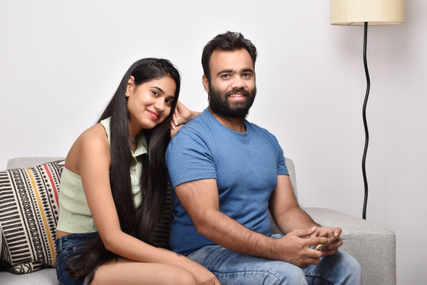 一对幸福的年轻夫妇坐在沙发上图片下载