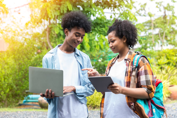 学生的生活。两个学生在学校用笔记本电脑工作，查看社交媒体。大学生使用笔记本电脑和平板电脑。图片下载