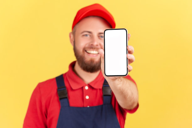 穿着制服的工人或修理工在空白的屏幕上显示手机和拷贝空间。图片下载