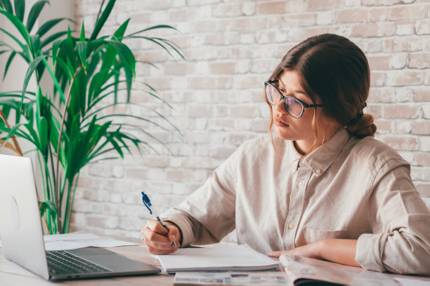 微笑的女人写笔记在笔记本电脑上看网络研讨会学习工作，年轻的学生学习计算机课程听力讲座培训翻译在线教师翻译班图片下载