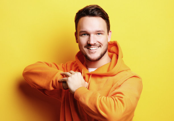 聪明的年轻人微笑着站在黄色的背景图片下载