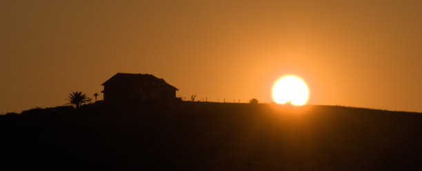 太阳从小山上的房子上冉冉升起图片下载